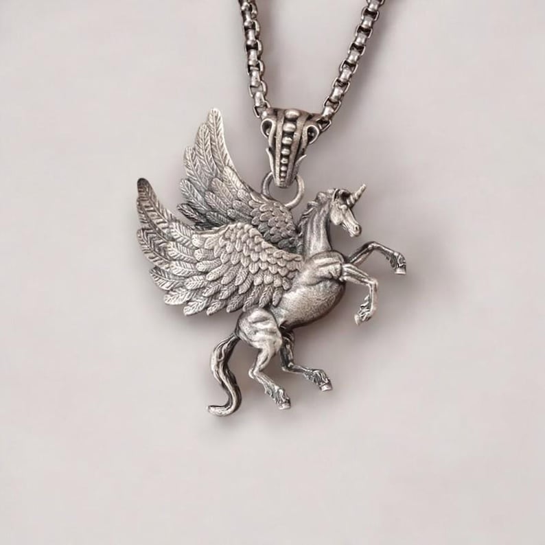 May include: Silver necklace featuring a detailed winged unicorn pendant. The pendant is a three-dimensional sculpture of a unicorn with wings.