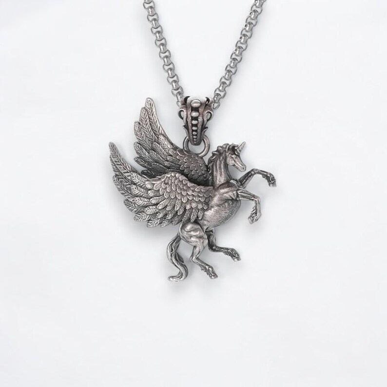 May include: A silver pendant necklace featuring a detailed winged horse design. The horse has a flowing mane and tail, and its wings are spread wide. The pendant is attached to a silver chain.