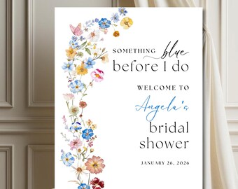 Puede incluir: Un cartel blanco con un borde floral y el texto "Something blue before I do" en letra cursiva negra. El cartel también incluye el texto "Welcome to Angela's bridal shower" en letra cursiva negra y la fecha "January 26, 2026" en letra cursiva azul.