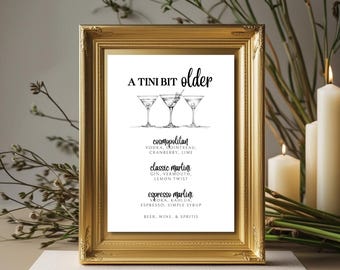 May include: A framed print with a gold ornate frame. The print features the text "A Tini Bit Older" above three martini glasses. Below the glasses are the recipes for Cosmopolitan, Classic Martini, and Espresso Martini cocktails.