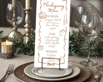 May include: A Thanksgiving menu card with a brown decorative border and text. The menu includes starter, main, and dessert options. The card is displayed on a white plate with a decorative metal stand, set on a table with silverware and candles.
