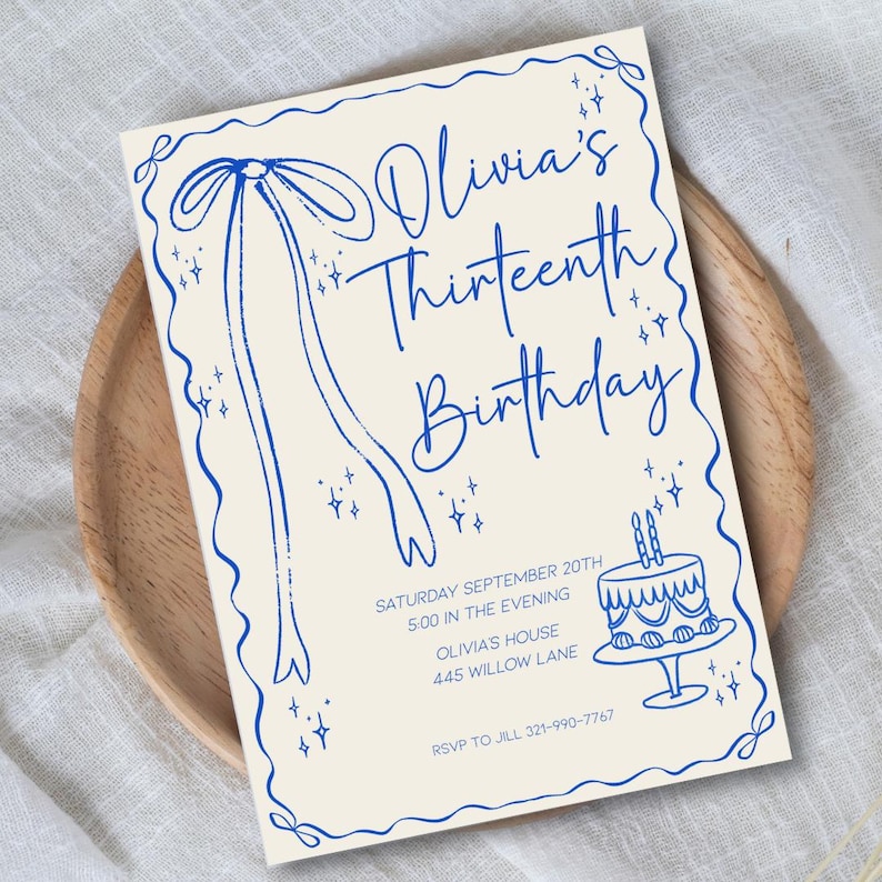 Op de afbeelding: Een cr&egrave;me verjaardagskaart met blauwe accenten. De tekst "Olivia's Thirteenth Birthday" is in een sierlijke lettertype geschreven. De kaart bevat datum, tijd, locatie en een telefoonnummer voor RSVP.