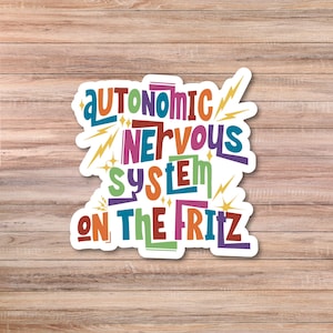 May include: A colorful sticker with the words "AUTONOMIC NERVOUS SYSTEM ON THE FRITZ" in various bright colors. The sticker has a white border and lightning bolt accents, set against a wooden background.