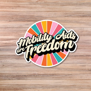 May include: A colorful sticker with a sunburst design and the text "Mobility Aids are Freedom" in a retro font.