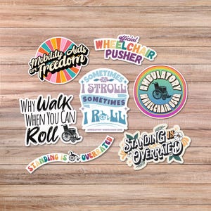 May include: A collection of colorful stickers with text and graphics related to mobility aids and wheelchair use. The stickers feature phrases like "Mobility Aids are Freedom" and "Why Walk When You Can Roll."