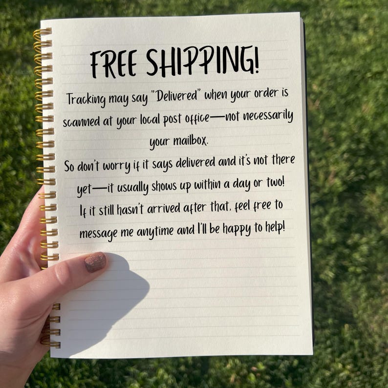 May include: A spiral-bound notebook with lined paper. The cover is not visible. The text "FREE SHIPPING!" is written at the top, followed by a message about order tracking. The notebook is held by a person.