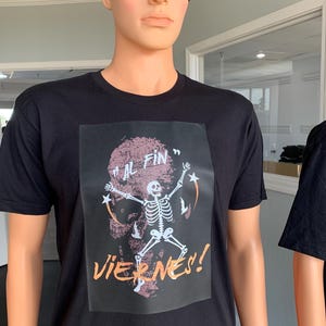 May include: Black t-shirt featuring a graphic print of a skeleton dancing with the text "Al Fin" and "Viernes!" in orange.