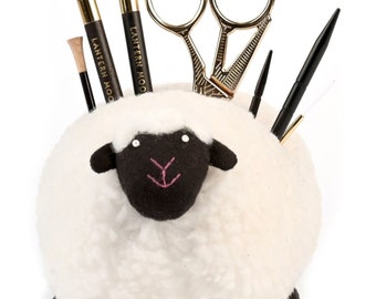 May include: White fluffy sheep-shaped needle minder with black eyes and nose, holding a pair of gold scissors, two gold needles, and a black needle. The needles are labeled "Lantern Moo".