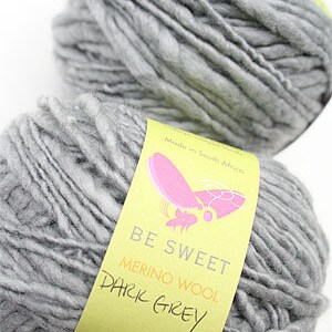 May include: Two skeins of dark grey merino wool yarn, labeled "Be Sweet Merino Wool Dark Grey".