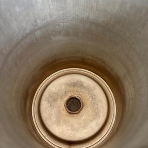 Puede incluir: Un recipiente cil&iacute;ndrico de acero inoxidable con base circular. El interior muestra signos de uso con algo de decoloraci&oacute;n. El recipiente tiene una abertura ancha y un accesorio central en la base.