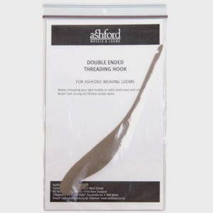 May include: A double-ended threading hook for Ashford weaving looms, packaged in a clear plastic bag. The hook is a light brown color and has a curved end. The packaging includes the "ashford WHEELS & LOOMS" logo and product information.