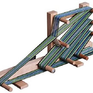 May include: A wooden loom with a green, blue, and white striped fabric woven on it. The loom has several wooden dowels for winding the fabric.