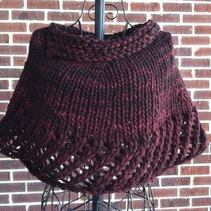 Puede incluir: Un chal de punto de color burdeos oscuro con cuello de tortuga y un patrón de encaje alrededor de los bordes.