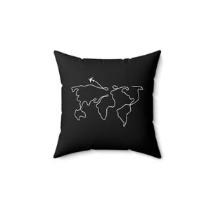Può includere: Cuscino nero con un contorno bianco di una mappa del mondo e un aereo che vola sopra.