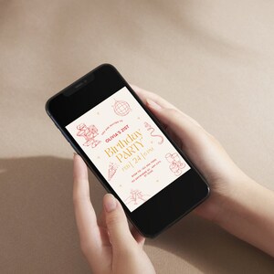 May include: A smartphone displaying a birthday party invitation for Olivia's 21st birthday party. The invitation features a gold and red color scheme with illustrations of party hats, confetti, and champagne glasses. The text reads "Olivia's 21st Birthday Party, Feb 24 | 6 PM".