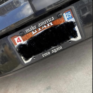 May include: A black license plate frame with the text "make america utah emo again" in white lettering. The frame is attached to a car with a Utah license plate.