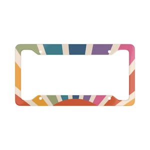 May include: A colorful rainbow sunburst design license plate frame. The frame is white with a rainbow sunburst design on the front. The frame has holes for screws to attach it to a license plate.