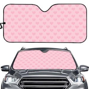 May include: Pink car sunshade with a pattern of small pink hearts. The sunshade is made of a lightweight material and is designed to block out the sun's rays.