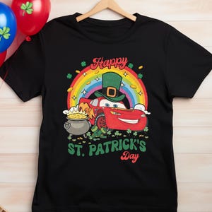May include: Black t-shirt with a red cartoon car wearing a green hat and holding a pot of gold. The car is in front of a rainbow with the text "Happy St. Patrick's Day".