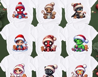 May include: A collection of nine white short-sleeved t-shirts, each featuring a different cartoon character wearing a winter hat and scarf. The characters include superheroes and figures holding mugs of hot cocoa and gingerbread cookies.