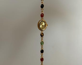 montre délicate en or et pierres multicolores