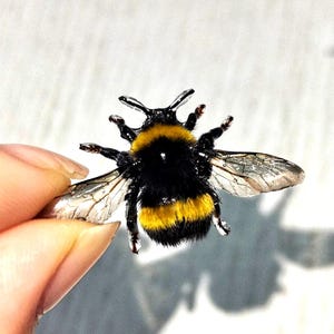 May include: A detailed close-up of a bumblebee, showcasing its black and yellow striped body and translucent wings. The bee is in focus, with fine details visible, suggesting a craft or nature-themed product.