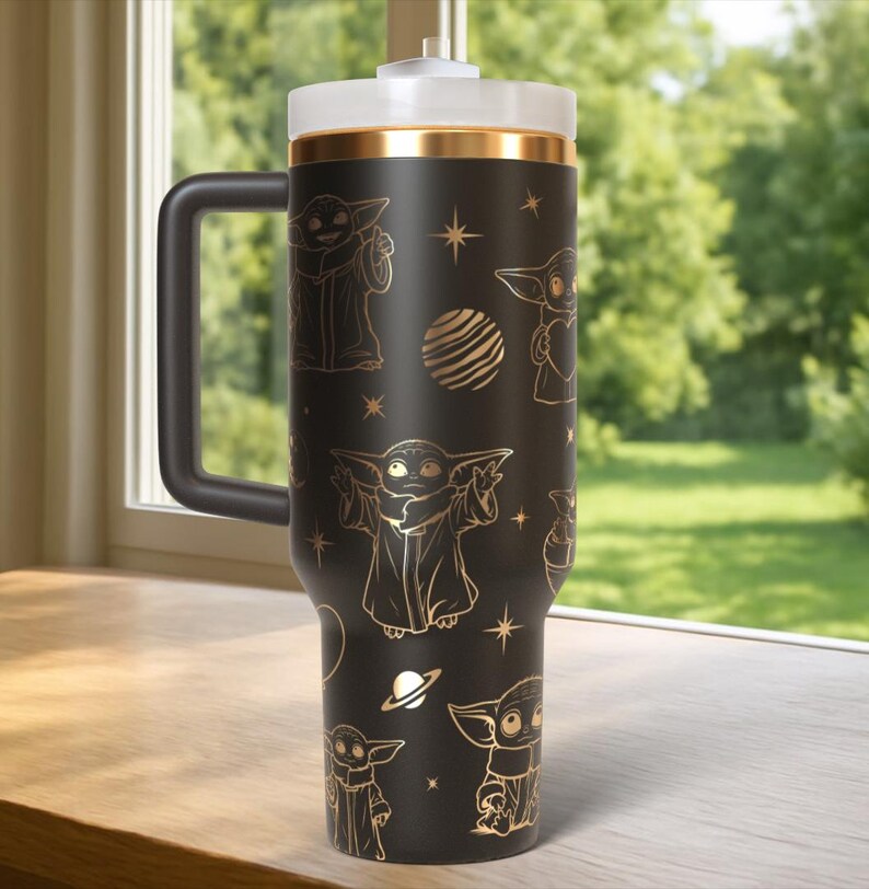 May include: A black travel mug featuring gold illustrations of a character, stars, and planets. The mug has a black handle, a white lid, and a gold band. The mug is designed to hold a large quantity of liquid.