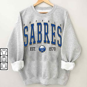 May include: Gray sweatshirt with a blue and gold Buffalo Sabres logo and the text "Buffalo Sabres Est. 1970".