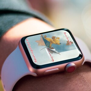 May include: A rose gold Apple Watch with a white band displays a Winnie the Pooh themed watch face. The watch face features a cartoon image of Winnie the Pooh holding a red balloon with the text "There is no hurry" and "We shall get there someday."