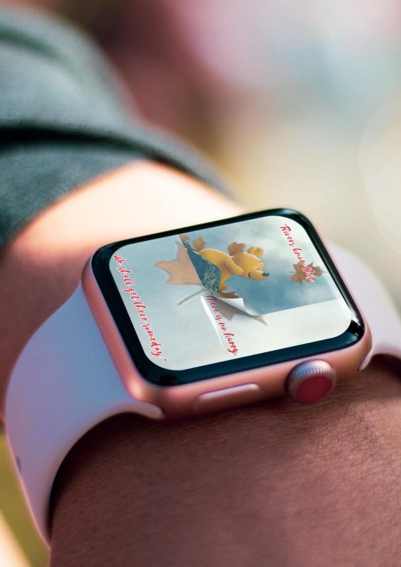 May include: A rose gold Apple Watch with a white band displays a Winnie the Pooh themed watch face. The watch face features a cartoon image of Winnie the Pooh holding a red balloon with the text "There is no hurry" and "We shall get there someday."