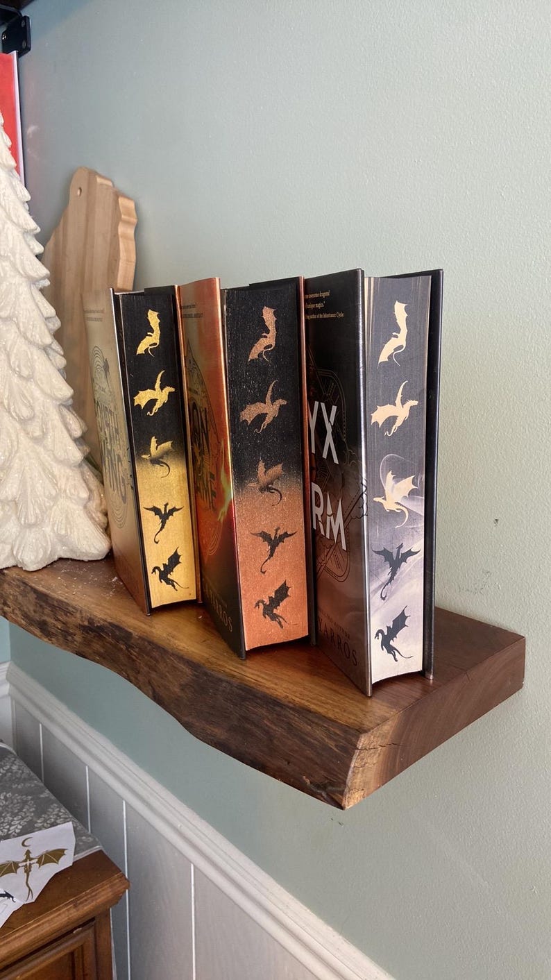 Puede incluir: Cuatro libros de tapa dura con cubiertas negras y dise&ntilde;os de dragones dorados, cobre y plata en las espinas. Los libros se titulan "The Inheritance Cycle" y "Eragon".