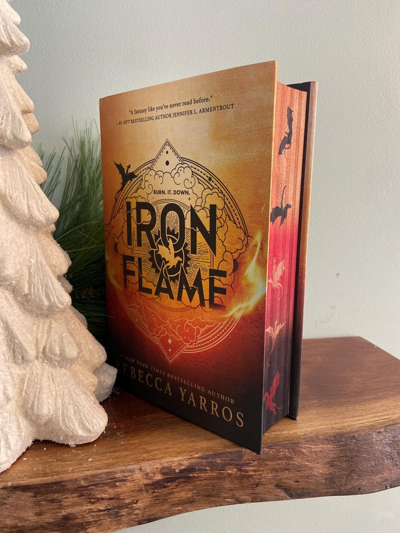 Puede incluir: Una novela de fantas&iacute;a titulada "Iron Flame" de la autora superventas del New York Times Rebecca Yarros. La portada presenta un fondo naranja y rojo fuego con un dise&ntilde;o circular negro y dorado. El texto "Burn. It. Down." est&aacute; escrito en negro sobre el t&iacute;tulo.