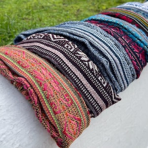 Puede incluir: Una pila de diademas tejidas de colores con intrincados patrones. Las diademas están hechas de una tela suave y texturizada y están disponibles en una variedad de colores y diseños.