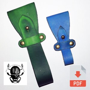 May include: Two leather belt loops, one larger in green and one smaller in blue, each featuring a pointed strap secured by two brass-colored metal rivets. The green loop is positioned on the left and the blue loop is on the right.