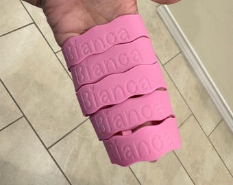 Könnte beinhalten: Fünf rosa Silikonarmbänder mit dem Namen "Bianca" auf jedem.