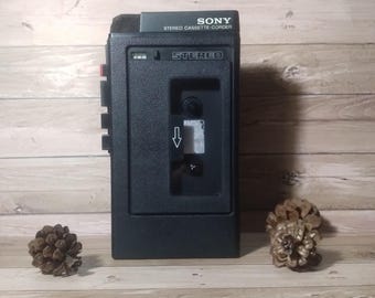 Puede incluir: Un reproductor de casetes estéreo Sony negro con el texto "SONY STEREO CASSETTE-CORDER" y "STEREO" en la parte delantera.