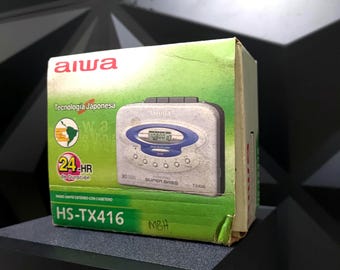 May include: A vintage Aiwa HS-TX416 portable cassette player with a digital display, Super Bass feature, and 24-hour duration. The player is housed in its original box, which features Japanese text and a green and white color scheme.
