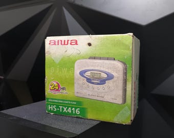 May include: A white and blue Aiwa HS-TX416 cassette player in its original box. The box is green and has the text "24-HR Long Play Battery Life" and "Super Bass" printed on it.