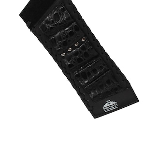 May include: Black leather watch strap with a crocodile skin pattern. The strap has a Velcro closure and metal studs. The brand name "Benny Truck Ltd" is printed on the strap.