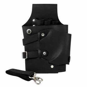 May include: Black leather barber tool holster with multiple compartments and a detachable shoulder strap. Features silver-tone metal rivets and a buckle closure. Designed to hold various grooming tools.
