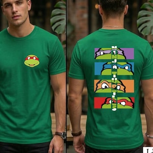 May include: Green t-shirt featuring a Teenage Mutant Ninja Turtle graphic on the front and back. The front displays a turtle face, while the back showcases four turtle faces with the text "NINJA TURTLES" vertically.