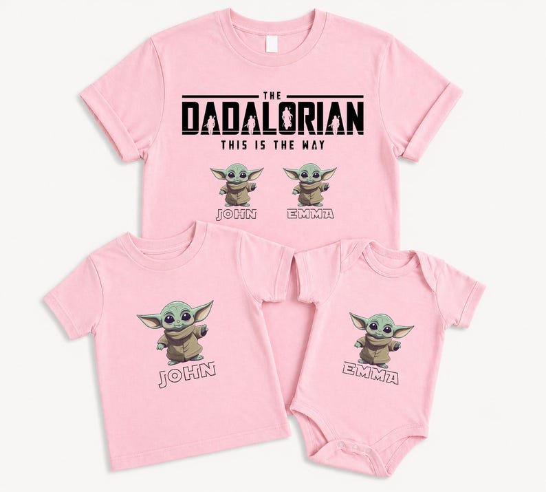 K&ouml;nnte beinhalten: Rosafarbene T-Shirts und ein Body mit einer Zeichentrickfigur. Die Shirts tragen den Text "THE DADALORIAN THIS IS THE WAY" und das Bild der Figur. Die Shirts sind mit "JOHN" und "EMMA" beschriftet.