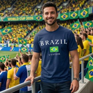 Może przedstawiać: Biały ceramiczny kubek z czarnym uchwytem i napisem "But First, Coffee" w stylu odręcznym. Kubek stoi na białej powierzchni. Kubek ma 10 cm wysokości.