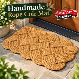 Puede incluir: Un felpudo rectangular hecho de cuerda de fibra de coco natural gruesa, tejida en un patrón denso y entrelazado. La alfombra presenta una superficie fibrosa y texturizada con un tono marrón claro consistente en toda su estructura tejida.