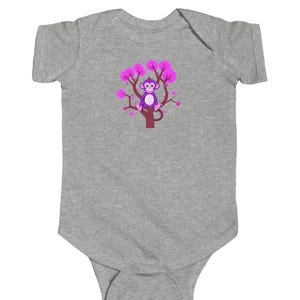 May include: A grey baby onesie with a purple monkey sitting on a pink tree with pink flowers.