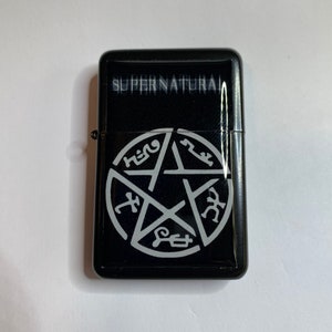 May include: Black lighter with a silver pentagram and the word "SUPERNATURAL" on the front.