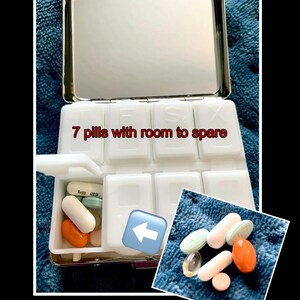 Puede incluir: Un organizador de pastillas blanco con tapa de espejo. El organizador tiene siete compartimentos y el texto "7 pastillas con espacio de sobra" est&aacute; impreso en la parte delantera. Hay varias pastillas en uno de los compartimentos.