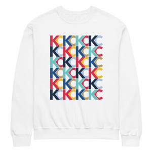May include: White sweatshirt with a repeating pattern of the letters "KCKC" in a variety of colours, including red, blue, yellow, and teal. The design is centred on the front of the crew neck sweatshirt.