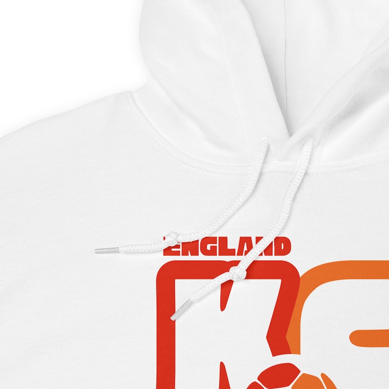 May include: White hooded sweatshirt with the word "ENGLAND" in red letters. The sweatshirt has a drawstring hood and a large orange and red graphic design. A soccer ball is visible in the design.