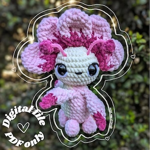 Könnte beinhalten: Ein gehäkeltes Amigurumi-Spielzeug in Form eines Axolotls. Der Axolotl ist rosa und weiß mit einer rosa Blume auf dem Kopf. Das Spielzeug sitzt auf einem grünen Hintergrund. Digitale Datei, nur PDF.